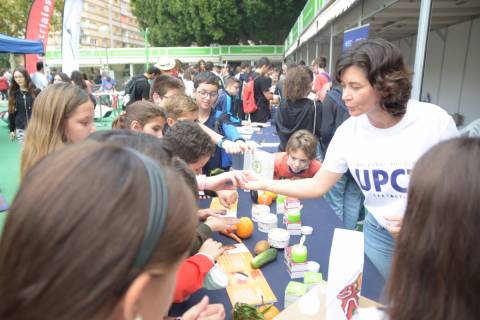 Encarna Aguayo explicando a unos menores en la Semana de la Ciencia cómo se reaprovechan alimentos en productos cosméticos sostenibles.